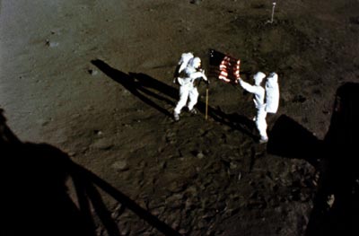 Neil A. Armstrong (vlevo) a Buzz Aldrin rozvinují vlajku Spojených států amerických poté, co Apollo 11 přistálo 20. července 1969 na Měsíci.